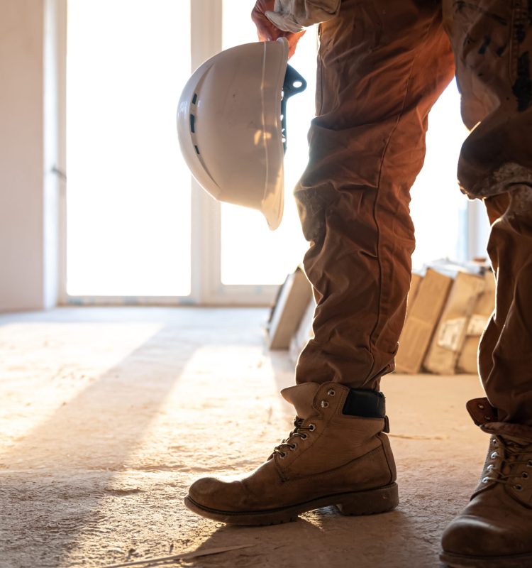 A man builder in work clothes at a construction site, copy space.